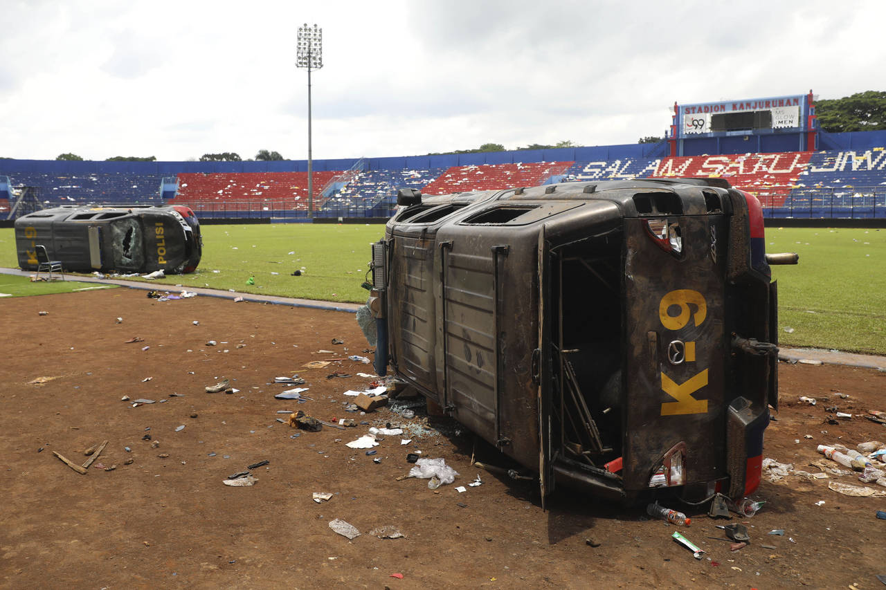 Police cars wrecked in soccer riots are seen on the pitch at Kanjuruhan Stadium in Malang, East Jav...