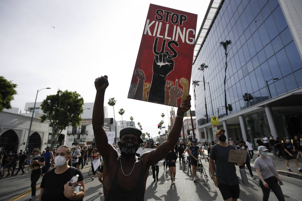 FILE - A protester carries a sign in the Hollywood area of Los Angeles on June 1, 2020, during demo...