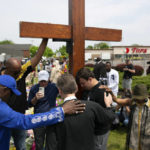 
              FILE - A group prays at the site of a memorial for the victims of the Buffalo supermarket shooting outside the Tops Friendly Market on Saturday, May 21, 2022, in Buffalo, N.Y. The victims of the mass shooting will be honored with a permanent memorial in the neighborhood. Gov. Kathy Hochul and Mayor Byron Brown on Friday, Oct. 21, 2022,  announced the creation of a commission tasked with planning and overseeing construction of a monument in East Buffalo. (AP Photo/Joshua Bessex, File)
            