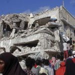 
              Relatives wait for bodies to be removed from the destruction at the scene, a day after a double car bomb attack at a busy junction in Mogadishu, Somalia Sunday, Oct. 30, 2022. Somalia's president says multiple people were killed in Saturday's attacks and the toll could rise in the country's deadliest attack since a truck bombing at the same spot five years ago killed more than 500. (AP Photo/Farah Abdi Warsameh)
            