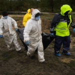 
              Members of a forensic team carry a plastic bag with a body inside as they work at an exhumation in a mass grave in Lyman, Ukraine, Tuesday, Oct. 11, 2022. (AP Photo/Francisco Seco)
            