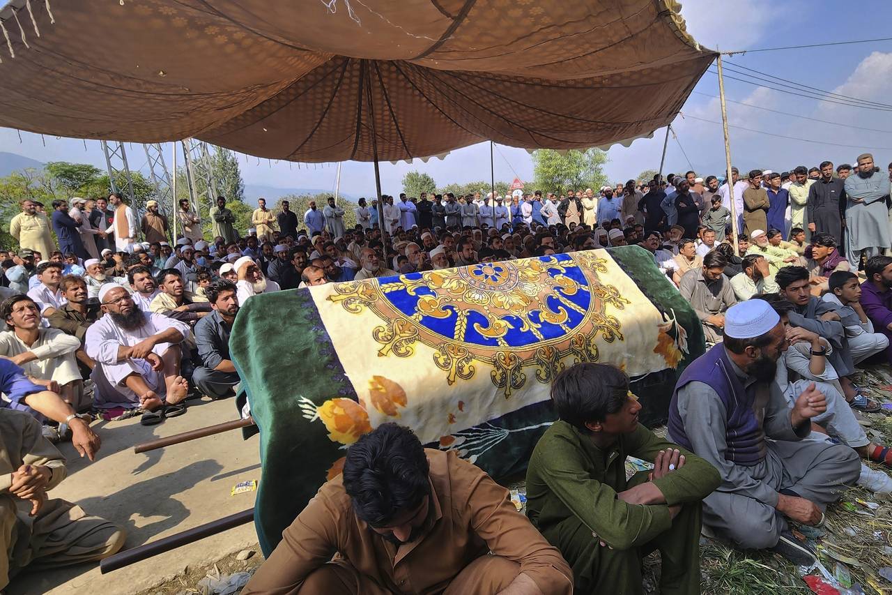 Relatives and residents gather with the body of a school van driver who was killed by a gunman in a...