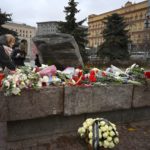 
              People lay flowers at a monument outside the former KGB headquarters, right, in Moscow, Russia, Saturday, Oct. 29, 2022, in an annual commemoration of the victims of purges under Soviet dictator Joseph Stalin. The monument is a large boulder from the Solovetsky islands, where the first camp of the Gulag political prison system was established. (AP Photo/Dmitry Serebryakov)
            