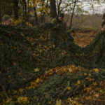 
              Ukrainian territorial defence deminers remove a camouflage net to be reused as they clear mines in an abandoned Russian camp near Hrakove village, Ukraine, Thursday, Oct. 13, 2022. (AP Photo/Francisco Seco)
            