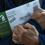 
              FILE — A Michigan voter clutches her absentee ballot before dropping it off at the city clerk's office in Warren, Mich., on Oct. 28, 2020. A total of 1.6 million people have requested absentee ballots so far this year, surpassing the 1.16 million who chose the option in the 2018 midterm election. (AP Photo/David Goldman, File)
            