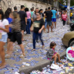 
              A girl sits on the sidewalk amidst electoral fliers as voters line up outside a polling station during general elections in Rio de Janeiro, Brazil, Sunday, Oct. 2, 2022. (AP Photo/Matias Delacroix)
            