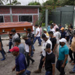 
              Residents carry the coffin of a person killed in a mass shooting in San Miguel Totolapan, Mexico, Thursday, Oct. 6, 2022. A drug gang bursted into the town hall and shot to death 20 people, including a mayor and his father, officials said Thursday. (AP Photo/Eduardo Verdugo)
            