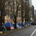 
              FILE - Tents line the sidewalk on SW Clay St in Portland, Ore., on Dec. 9, 2020. Portland Mayor Ted Wheeler announced this morning Friday, Oct. 21, 2022, that the city will ban homeless street camping in the coming months as it creates new, large "designated" camping sites in a bid to address the city's homelessness crisis. (AP Photo/Craig Mitchelldyer, File)
            