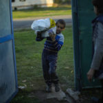 
              A young boy carries a bag with food given by Ukrainian volunteers in recently retaken Pidlyman village, east Ukraine, Friday, Oct. 7, 2022. (AP Photo/Francisco Seco)
            