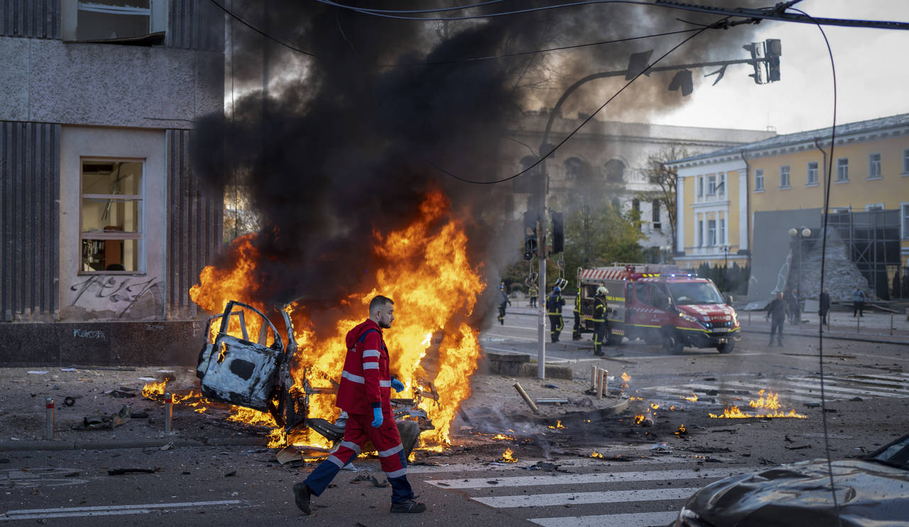 FILE - A medical worker runs past a burning car after a Russian attack in Kyiv, Ukraine, Monday, Oc...