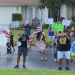 
              In this photo provided by former Sarasota County School Board Chair Shirley Brown, Proud Boy member James Hoel and others gather outside her home for an anti-mask protest on Oct. 4, 2021. "We see you in there, Shirley. We want you to come out for a redress of grievances," Hoel said through a megaphone. (Shirley Brown via AP)
            