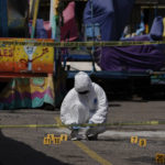 
              A forensics investigator works the scene of a massive shootout in San Miguel Totolapan, Mexico, Thursday, Oct. 6, 2022. A drug gang burst into the town hall and shot to death 20 people, including a mayor and his father, officials said Thursday. (AP Photo/Eduardo Verdugo)
            