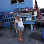 
              David Newcomb, who had worked as an assistant on the docks at Erickson & Jensen Seafood but now says he will return to Texas, sits in front of piles of clothing donated to help those in the shrimping community who lost everything, on San Carlos Island in Fort Myers Beach, Fla., Friday, Oct. 7, 2022. After the storm, many in the local shrimp industry find themselves not only out of work, but also left homeless, with most of the boats where they lived aboard left stranded on dry ground or heavily damaged.(AP Photo/Rebecca Blackwell)
            