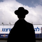 
              An ultra-Orthodox Jewish man walks by an election campaign billboard showing Itamar Ben-Gvir, Israeli far-right lawmaker and the head of "Jewish Power" party, in Bnei Brak, Israel Monday, Oct. 24, 2022. Israel is holding its fourth election in less than two years. Israel's most extremist politician, known for his inflammatory anti-Arab speeches and stunts, is attracting new supporters from a previously untapped demographic young ultra-Orthodox Jews, one of the fastest-growing segments of the country's population. (AP Photo/Oded Balilty)
            