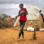 
              A boy stands near shelters at a camp for displaced people on the outskirts of Dollow, Somalia, on Tuesday, Sept. 20, 2022. Within weeks, a famine could be declared in Somalia, affecting hundreds of thousands of people. Such a declaration is rare and a sign of the dire consequences from the worst drought in decades in the Horn of Africa. (AP Photo/Jerome Delay)
            