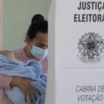
              A woman holding a baby votes during general elections, in Acegua, Brazil, Sunday, Oct. 2, 2022. (AP Photo/Matilde Campodonico)
            