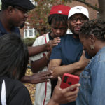
              Messiah Miller, 16, center, a junior at Central Visual & Performing Arts High School, prays with his teacher Ray Parks, second from right, following a shooting at the school on Monday, Oct. 24, 2022, in the Southwest Garden neighborhood. "He looked at me, he pointed the gun at me," said Parks, a dance teacher, who came face to face with the gunman. (Robert Cohen/St. Louis Post-Dispatch via AP)
            