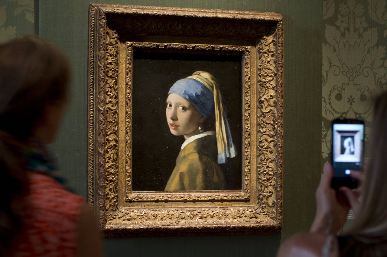 FILE- Visitors take pictures of Johannes Vermeer's Girl with a Pearl Earring (approx. 1665) during ...