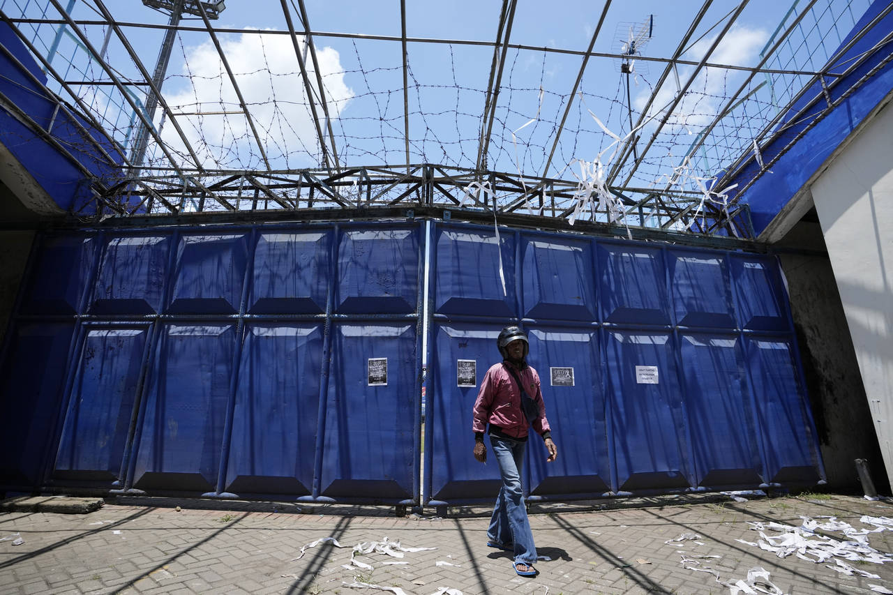 A man walks in front of gate at the Kanjuruhan Stadium in Malang, Indonesia, Tuesday, Oct. 4, 2022....