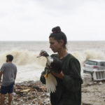 
              A woman saves a bird on a beach following heavy thunderstorms, in the village of Paliokastro, on the island of Crete, Greece, Saturday, Oct. 15, 2022. It has been reported that at least one person has died with others missing due to the severe flooding. (AP Photo/Harry Nakos)
            