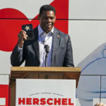 
              FILE - Herschel Walker, Republican candidate for U.S. Senate in Georgia, flashes a police badge as he speak to supporters during a campaign rally Oct. 18, 2022, in Atlanta. Walker campaigns for the U.S. Senate as a champion of free enterprise and advocate for the mentally ill, felons and others. And the Georgia Republican has called for policies that blend those priorities. Yet Walker, through a major chicken processor that he touts as a principal partner to one of his primary businesses,  has benefited from years of unpaid labor by drug offenders routed to the facility by Oklahoma state courts.(AP Photo/John Bazemore, File)
            