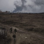 
              FILE - Soldiers walk on a path as smoke billows from the town of Irpin, on the outskirts of Kyiv, Ukraine, Saturday, March 12, 2022. The northwest suburbs of the capital, such as Irpin and Bucha had endured Russian shellfire and bombardment, prompting residents to leave their homes. (AP Photo/Felipe Dana, File)
            