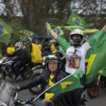 
              Supporters of Brazilian President Jair Bolsonaro wave Brazilian flags during a motorcycle campaign rally in Pocos de Caldas, Brazil, Friday, Sept. 30, 2022. Brazil’s Oct. 2 presidential election is being contested by 11 candidates but only two stand a chance of reaching a runoff: former President Luiz Inacio Lula da Silva and incumbent Jair Bolsonaro. (AP Photo/Victor R. Caivano)
            