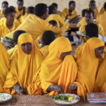 
              Students eat at a school in Dollow, Somalia, on Monday, Sept. 19, 2022. At midday, dozens of hungry children from the camps try to slip into a local primary school where the World Food Program offers a rare lunch program for students. (AP Photo/Jerome Delay)
            