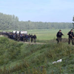 
              In this photo provided by the Serbian Ministry of Interior, Serbian Police officers escort migrants near village of Srpski Kustur, Serbia, Wednesday, Oct 5, 2022. Serbian police on Wednesday raided a make-shift camp near the border with Hungary where they found 200 migrants, detained people smugglers and confiscated weapons and money. (Serbian Ministry of Interior via AP)
            