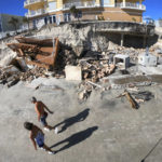 
              Beachgoers walk past a collapsed pool deck Monday, Oct. 3, 2022, in Daytona Beach Shores, Fla., as hotel and condo seawalls and decks along the Volusia County coastline were gutted by Hurricane Ian last week. (Joe Burbank/Orlando Sentinel via AP)
            