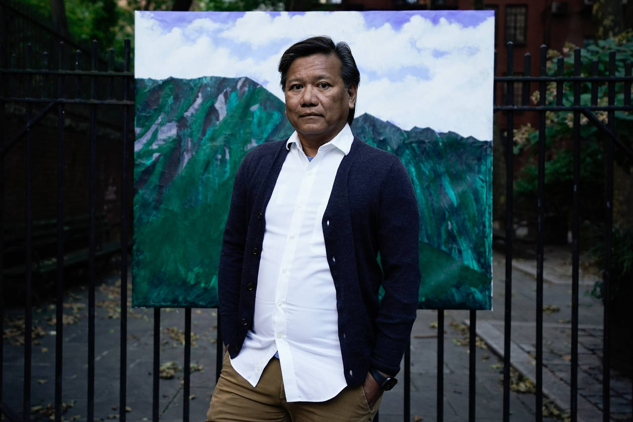Bobby Calvan poses in front of a painting of the view from his childhood home in Waimanalo, Hawaii,...