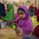 
              A child eats at a school in Dollow, Somalia, on Monday, Sept. 19, 2022. At midday, dozens of hungry children from the camps try to slip into a local primary school where the World Food Program offers a rare lunch program for students. (AP Photo/Jerome Delay)
            