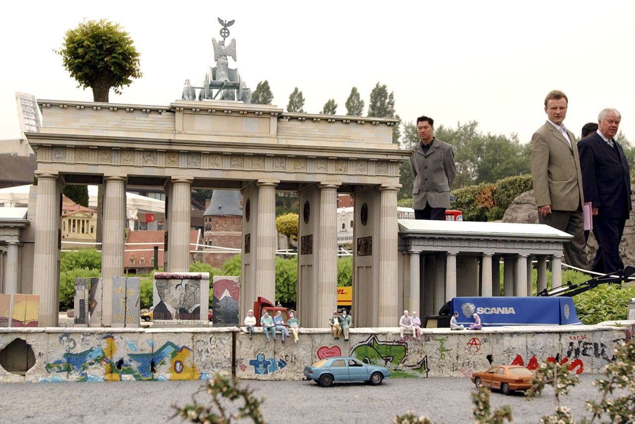 FILE - Visitors walk by a replica of the Brandenberg Gate and the Berlin wall at Mini-Europe in Bru...