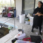
              Sivan Cohen looks our from her pool deck as she tries to dry water logged belongings, Monday, Oct. 3, 2022, in Fort Myers, Fla. The canal next to her home crested at 12 feet on Wednesday as Hurricane Ian ravaged the area. (AP Photo/Marta Lavandier)
            