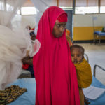 
              A woman holds a child at a clinic in Dollow, Somalia, on Wednesday, Sept. 21, 2022. Somalia is in the midst of the worst drought anyone there can remember. A rare famine declaration could be made within weeks. Climate change and fallout from the war in Ukraine are in part to blame. (AP Photo/Jerome Delay)
            