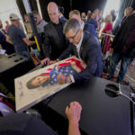 
              Michael Flynn, a retired three-star general who served as President Donald Trump’s national security advisor, autographs a picture of a girl wrapped in an American flag during the ReAwaken America Tour at Cornerstone Church in Batavia, N.Y., Friday, Aug. 12, 2022. Flynn, one of the tour’s founders and its star, warned the crowd that they were in the midst of a “spiritual war” and urges people to get involved in local politics." (AP Photo/Carolyn Kaster)
            