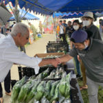 
              U.S. Ambassador to Japan Rahm Emanuel shakes hands with a local vendor at the farmers market at Camp Hansen, a U.S. Marine Corps base on a southern Japanese island of Okinawa, Sunday, Oct. 30, 2022. (U.S. Embassy via AP)
            