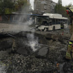 
              FILE - Firefighters and police officers work at a site where an explosion created a crater on the street after a Russian attack in Dnipro, Ukraine, Monday, Oct. 10, 2022. (AP Photo/Leo Correa, File)
            