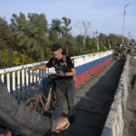 
              A man hauls his bicycle on a destroyed bridge across Oskil river during evacuation in recently liberated town Kupiansk, Ukraine, Saturday, Oct. 1, 2022. (AP Photo/Evgeniy Maloletka)
            