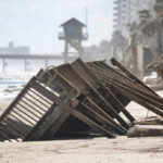 
              Beachgoers survey the damage Monday, Oct. 3, 2022, in Daytona Beach Shores, Fla., as hotel and condo seawalls and pool decks along the Volusia County coastline were gutted by Hurricane Ian last week. (Joe Burbank/Orlando Sentinel via AP)
            