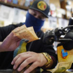 
              Store clerk Eduardo Duran rubs purchased lottery tickets on the head of the store lucky bluebird for the drawing of the Powerball lottery at the Blue Bird Liquor store in Hawthorne, Calif., Monday, Oct. 31, 2022. The jackpot for Monday night's drawing soared after no one matched all six numbers in Saturday night's drawing. It's the fifth-largest lottery jackpot in U.S. history. (AP Photo/Damian Dovarganes)
            