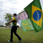 
              A woman holds a Brazilian flag and another with the image of Brazilian President Jair Bolsonaro, who is running for another term, after general election polls closed in Brasilia, Brazil, Sunday, Oct. 2, 2022. (AP Photo/Ton Molina)
            