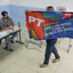 
              A voter displays a flag of the Workers Party of former Brazilian President Luiz Inacio Lula da Silva, who is running for president again, before voting in the general election in Sao Paulo, Brazil, Sunday, Oct. 2, 2022. (AP Photo/Andre Penner)
            
