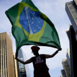 
              Ana Luiza Grace, supporter of Brazil's former President Luiz Inacio Lula da Silva, who is running for president again, holds a Brazilian flag after the closing of the polls for a presidential run-off election in Sao Paulo, Brazil, Sunday, Oct. 30, 2022. On Sunday, Brazilians had to choose between da Silva and his rival, incumbent President Jair Bolsonaro, after neither got enough support to win outright in the Oct. 2 general election.(AP Photo/Matias Delacroix)
            