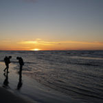 
              The sun sets in the horizon as Ned Ahgupuk and his girlfriend, Kelsi Rock, piggybacking their 1-year-old son, Steven, stroll along the beach on the Arctic Ocean in Shishmaref, Alaska, Friday, Sept. 30, 2022.  Rising sea levels, flooding, increased erosion and loss of protective sea ice and land have led residents of this island community to vote twice to relocate. But more than six years after the last vote, Shishmaref remains in the same place because the relocation is too costly. (AP Photo/Jae C. Hong)
            