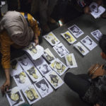 
              People looking for their family members inspect photographs of a soccer match stampede victims provided by volunteers to help them identify their relatives in Malang, East Java, Indonesia, Sunday, Oct. 2, 2022. Panic at an Indonesian soccer match Saturday left over 100 people dead, most of whom were trampled to death after police fired tear gas to prevent violence. (AP Photo/Dicky Bisinglasi)
            