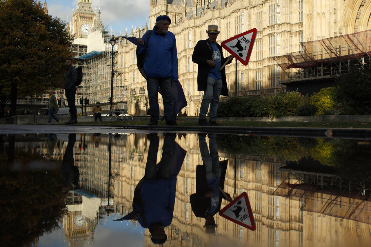 Protestors are reflected in a puddle opposite parliament after Britain's Prime Minister Liz Truss r...