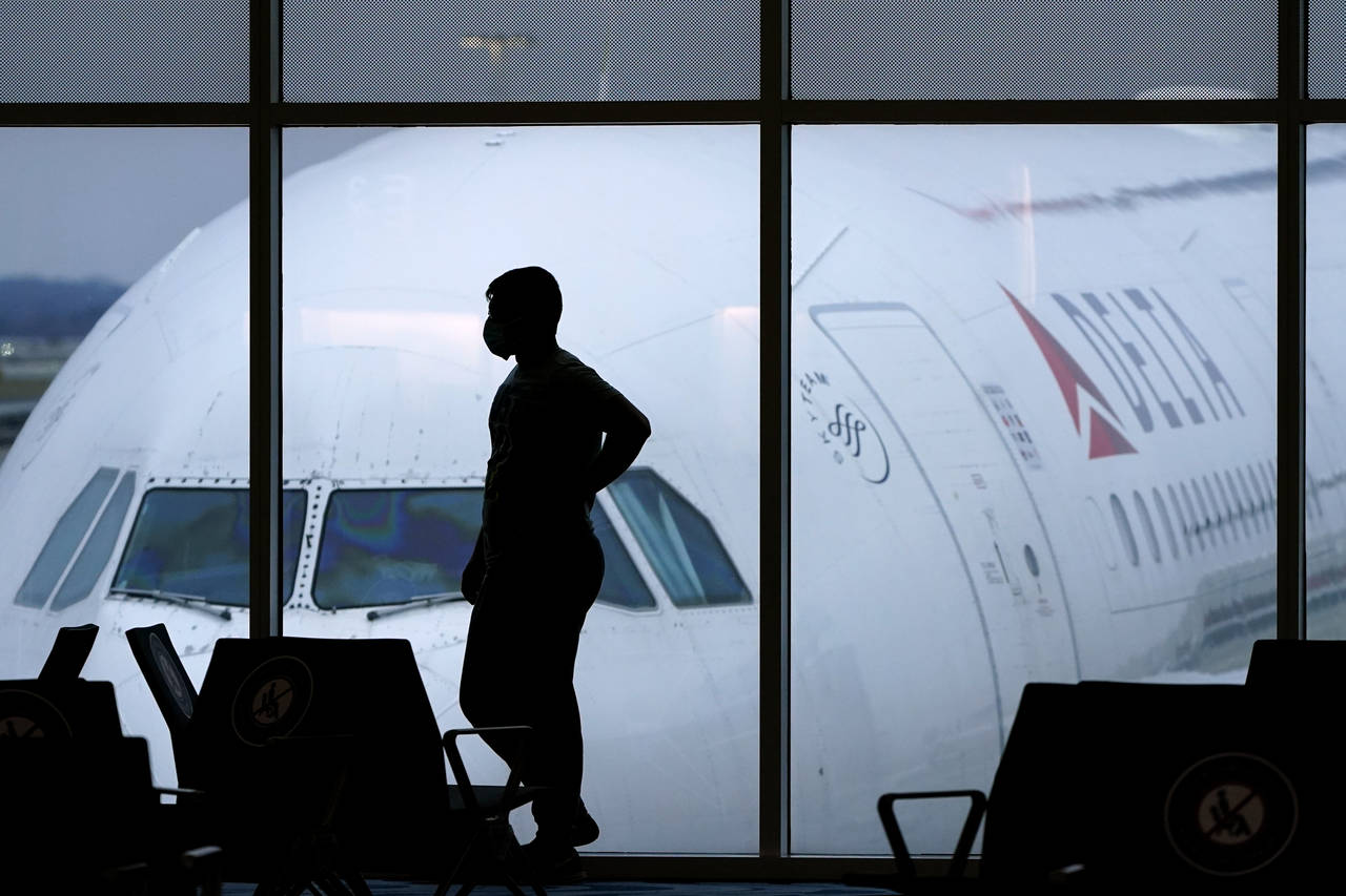 FILE - A passenger wears a face mask to help prevent the spread of the new coronavirus as he waits ...