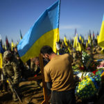 
              A man places a Ukrainian flag in the grave of recently killed Ukrainian serviceman Vadim Bereghnuy, 22, during his funeral in a cemetery in Kharkiv, Ukraine, Monday, Oct. 17, 2022. (AP Photo/Francisco Seco)
            