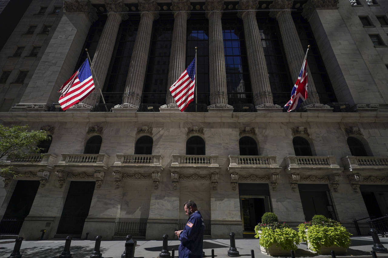 FILE - A trader looks over his cell phone outside the New York Stock Exchange, Wednesday, Sept. 14,...